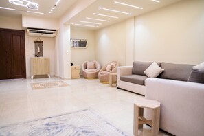 A modern living room with a sofa, two armchairs, a small table, and a decorative rug. - Deluxe Twin Room with Panoramic View (Sheikh Zayed City)