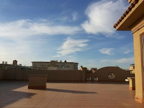 An outdoor terrace with a tiled floor, a wall with a circular window, and a clear sky. - Sky Studio | Cairo Keys New Cairo Residence (New Cairo City)