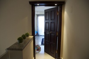 A hallway with a dark wooden door leading to a room with a bed and a window. - Sky Studio | Cairo Keys New Cairo Residence (New Cairo City)