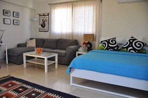 A bedroom with a bed, a sofa, a coffee table, and a lamp. - Sky Studio | Cairo Keys New Cairo Residence (New Cairo City)