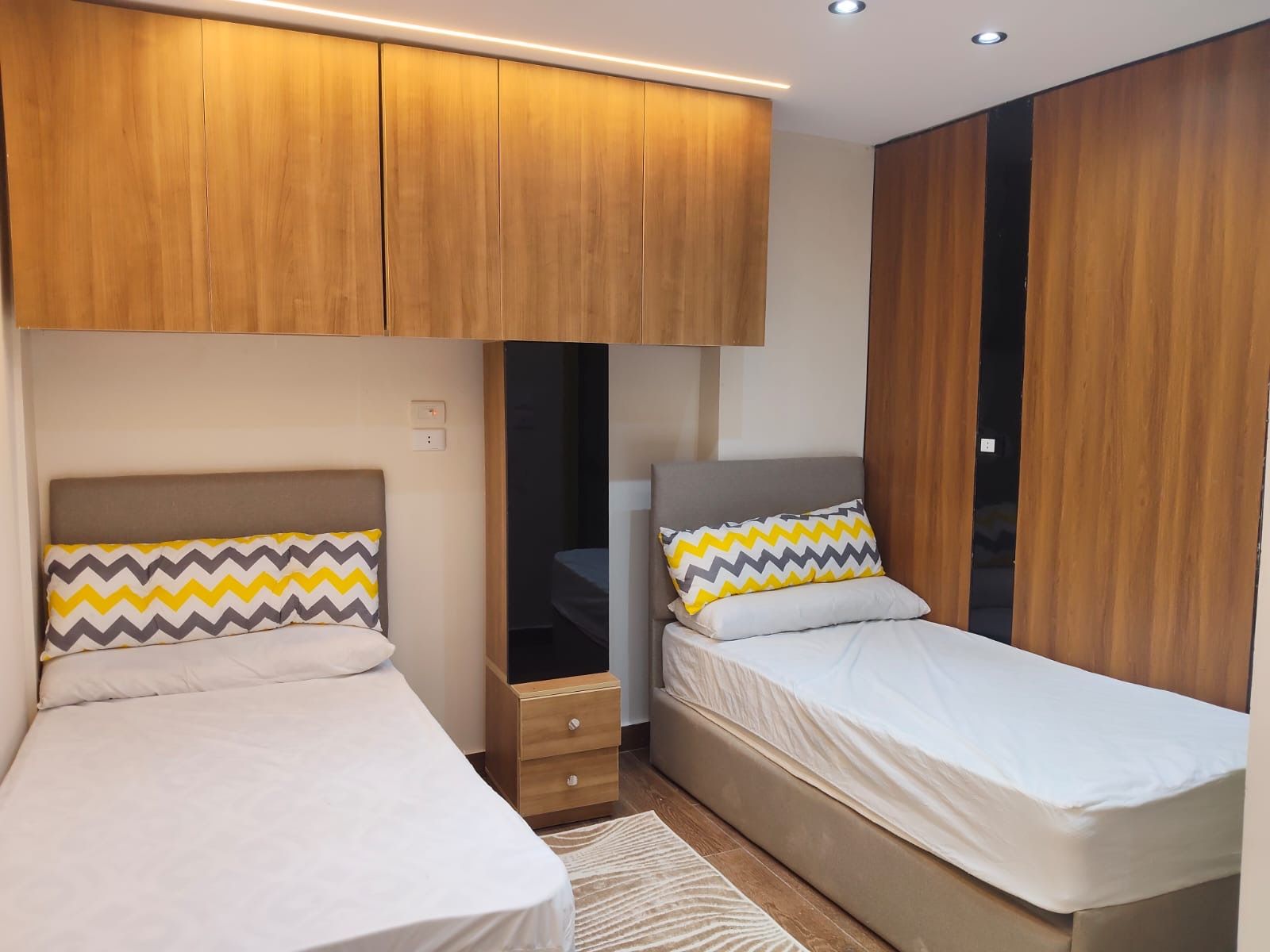 Un dormitorio con dos camas, armarios de madera y una mesita de noche.