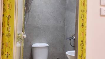 A bathroom with a toilet, a sink, and a shower enclosure.