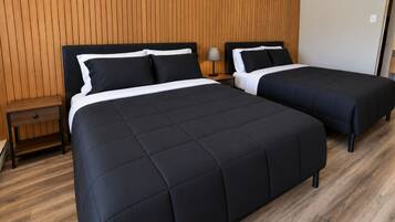 Ein Hotelzimmer mit zwei Betten, einer Holzwand, einem Nachttisch und einer Lampe.