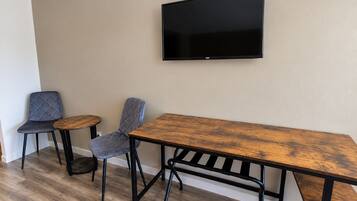 A room with a wooden table, two chairs, and a mounted television on the wall.