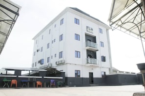 A multi-story hotel with a flat facade, balconies, and a covered outdoor seating area. - Jcwellington Hotel & Suite (Lagos)