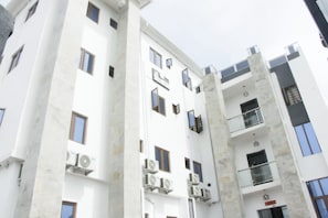 A multi-story building with balconies, air conditioning units, and a clear sky.