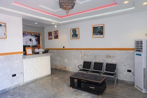 A reception area with a marble floor, a reception desk, framed portraits on the wall, and a chandelier.