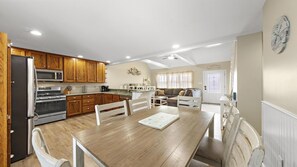 A modern kitchen with wooden cabinets, a dining table, and a living area with a sofa. - Large cape close to the beach & bay . Easy on & off the Island (Ship Bottom)