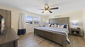 A bedroom with a bed, a ceiling fan, a nightstand, a TV, and a window with curtains. - Large cape close to the beach & bay . Easy on & off the Island (Ship Bottom)