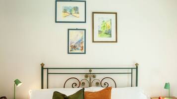 Ein Schlafzimmer mit einem Bett, einem Nachttisch, einer Lampe und drei gerahmten Kunstwerken an der Wand.