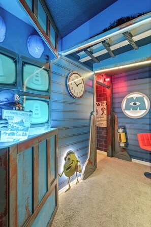 A room with a clock, a poster, a lamp, and a character. - Brand New Disney-Themed 8BR Home | Windsor Cay (Clermont)