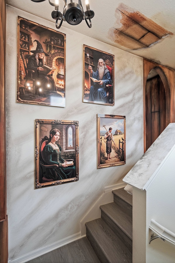 A staircase with a handrail and a wall with four framed paintings. - Brand New Disney-Themed 8BR Home | Windsor Cay (Clermont)