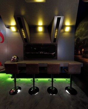 Un espace bar au design moderne, comprenant un comptoir, des tabourets et un éclairage d’ambiance.