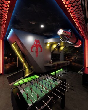 Ein Zimmer mit Tischfußballtisch, Barbereich und einem außergewöhnlichen Deckenstil.