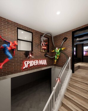A staircase with a Spiderman-themed wall decoration, including a Spiderman sign and a character in a web-slinging pose. - Brand New 8BR | Disney-Themed Home (Clermont)