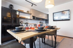 A modern kitchen with a dining table set for four, a refrigerator, and a television mounted on the wall. - Fabulous 5-bedroom apartment in charming Providencia neighborhood (Providencia)