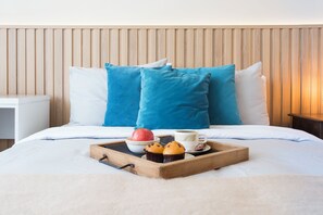 A neatly made bed with a wooden headboard, white bedding, and blue pillows. A tray with a muffin, an apple, and a cup of coffee is placed on the bed. - Fabulous 5-bedroom apartment in charming Providencia neighborhood (Providencia)