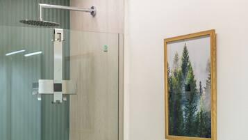 Une douche avec une paroi en verre et un tableau encadré représentant des arbres accroché au mur.