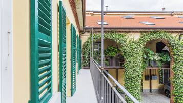Un corridoio stretto con un balcone, persiane verdi e un tetto in tegole.