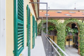 A narrow corridor with a balcony, green shutters, and a tiled roof. - Civico Due - Apartment (Cuneo)