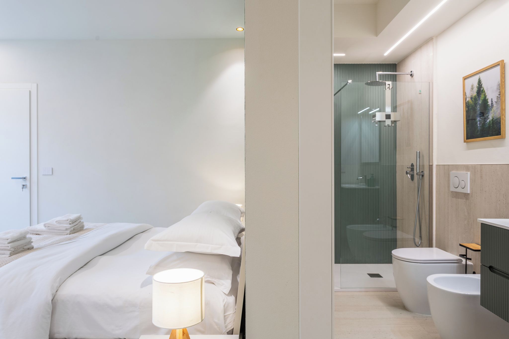 Una moderna camera d'albergo con un letto, una lampada da comodino, una zona doccia e un WC.