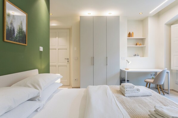 A hotel room with a bed, a desk, a chair, and a wardrobe. - Civico Due - Apartment (Cuneo)