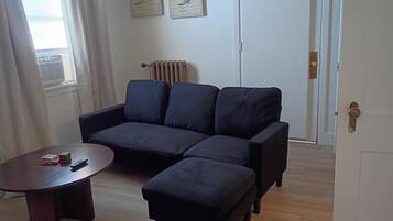A living room with a dark-colored sofa, a small round coffee table, and a radiator.