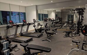 A gym with treadmills, weight machines, and free weights. - One Uptown Residence 24N (Taguig City)