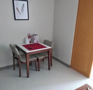 A small dining area with a table, four chairs, a red placemat, a framed picture on the wall, and a bottle and box on the table. - One Uptown Residence 31O (Taguig City)