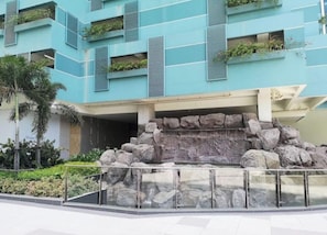 A modern building with balconies, a rock feature, and a glass railing. - One Uptown Residence 31O (Taguig City)