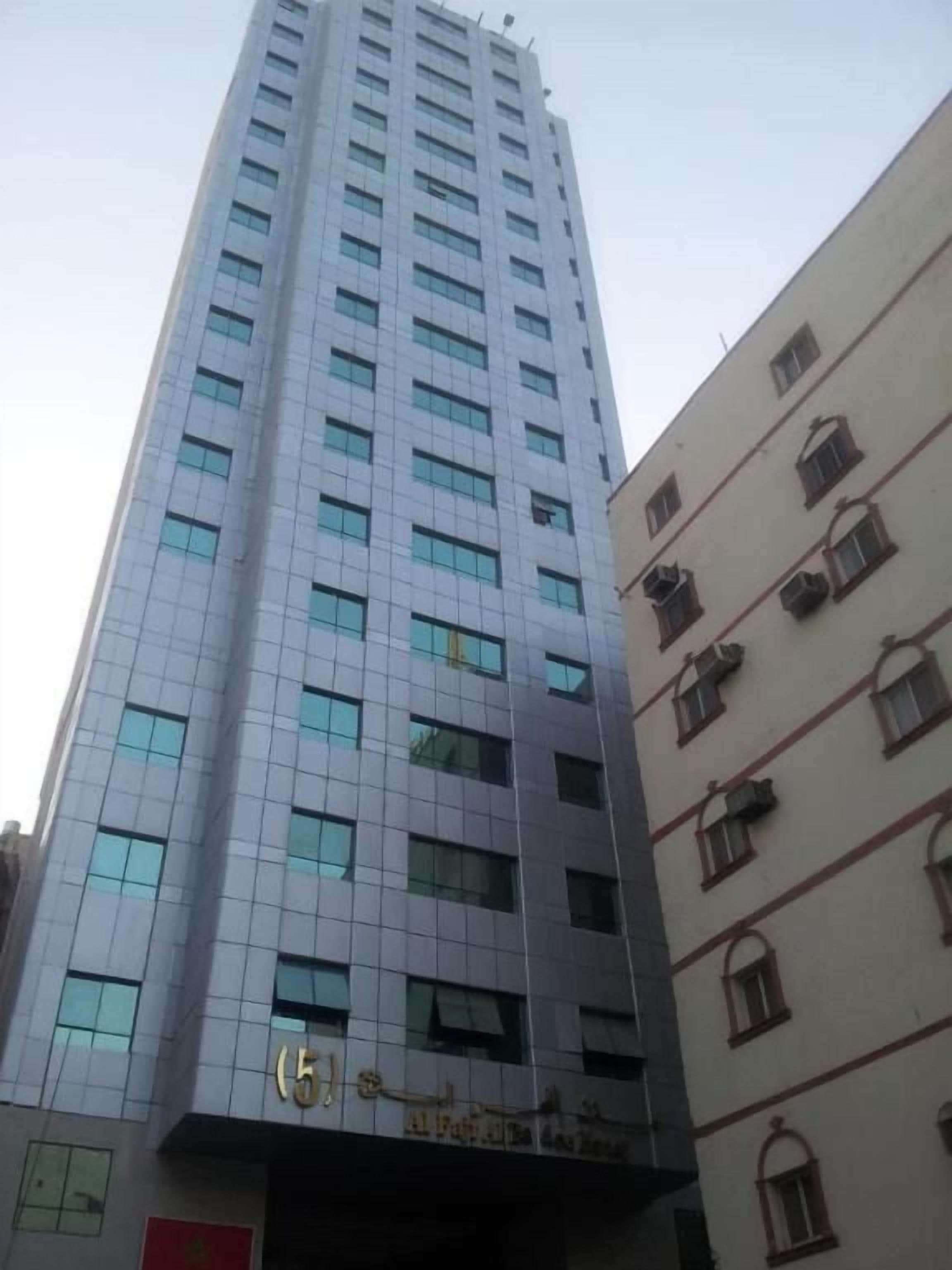Un edificio alto con fachada moderna, múltiples ventanales y una entrada visible con señalización.