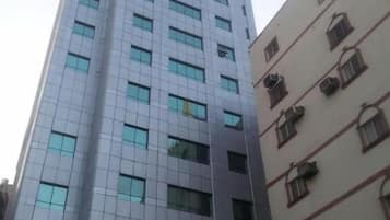 Un edificio alto con fachada moderna, múltiples ventanales y una entrada visible con señalización.