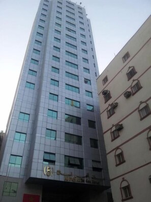 Un edificio alto con fachada moderna, múltiples ventanales y una entrada visible con señalización.