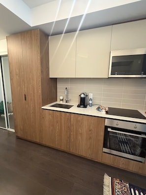 A modern kitchen with wooden cabinets, a built-in microwave, and a dishwasher. - Stylish 1bed 1bath | pool|gym | Central (Toronto)