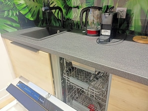 A kitchen with a built-in dishwasher, a kettle, and a coffee maker. - Apartament Radiostacja VI, trzypokojowe, klimatyzacja, parking free (Gliwice)