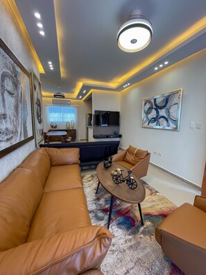 A modern living room with a leather sofa, a coffee table, and a television.