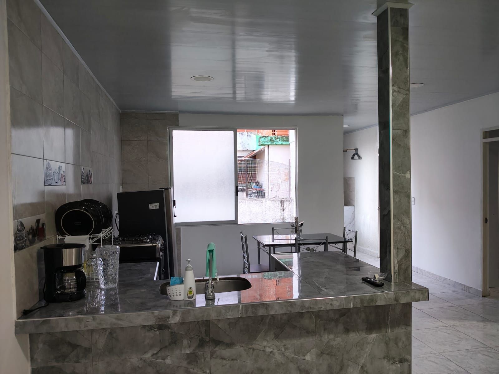 A kitchen with a marble countertop, a sink, and a window with a view of the outside.