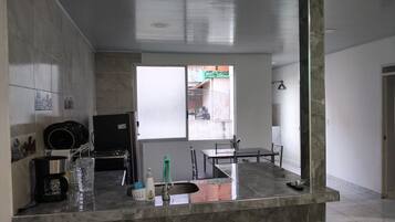 A kitchen with a marble countertop, a sink, and a window with a view of the outside.