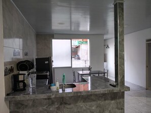 A kitchen with a marble countertop, a sink, and a window with a view of the outside. - MORADA CELESTIAL HOUSE is an apartment, perfect for family outings. (Ibagué)