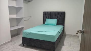 A bedroom with a bed, a window, and built-in shelving.