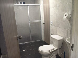 A bathroom with a toilet, a shower enclosure, and a toilet paper holder. - MORADA CELESTIAL HOUSE is an apartment, perfect for family outings. (Ibagué)