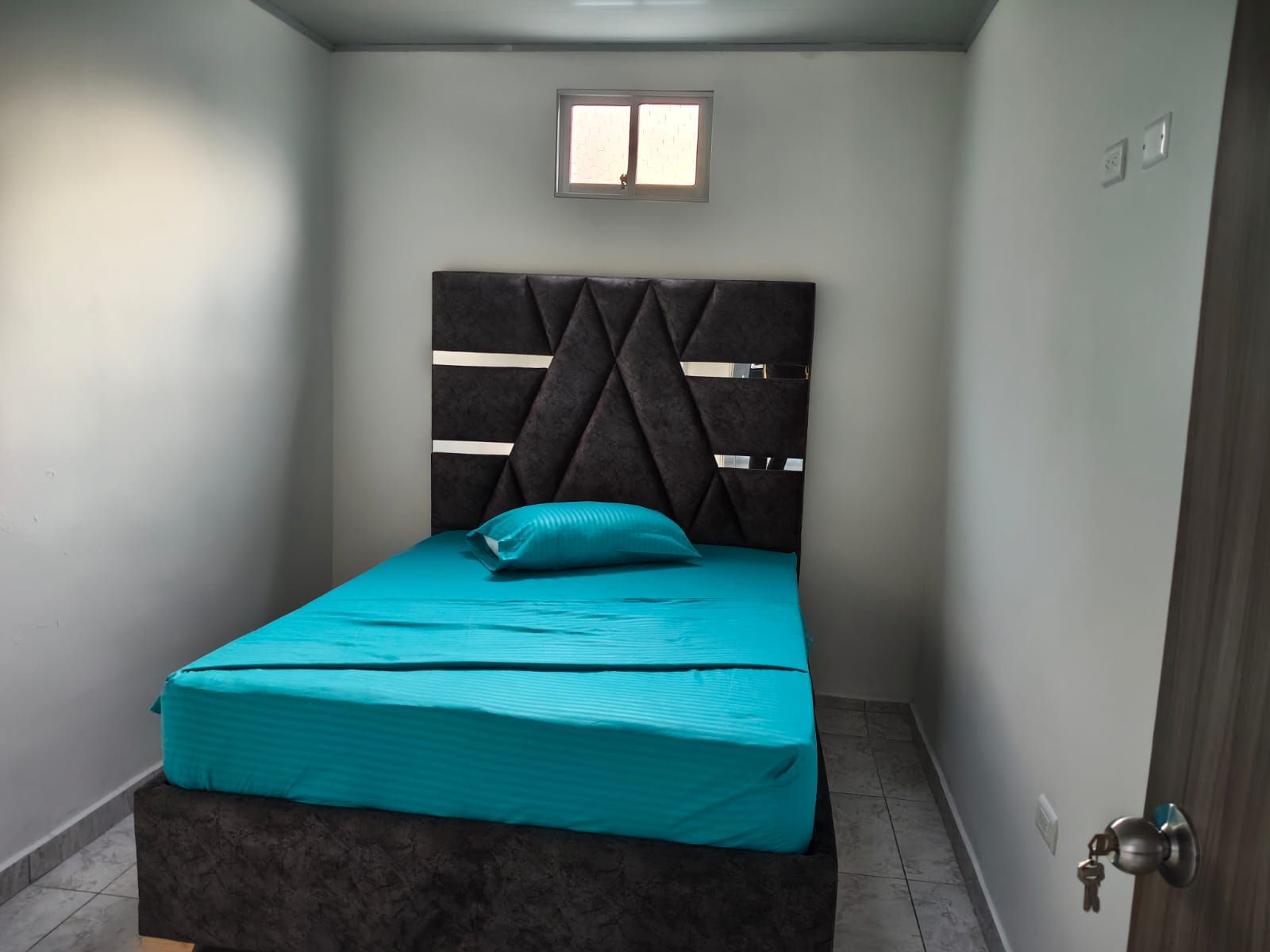 Une pièce avec un lit, une fenêtre et une porte.