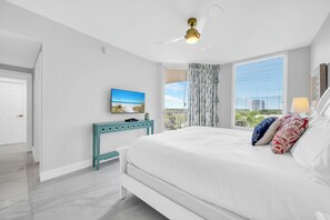 Ein Schlafzimmer mit Bett, Fernseher, Schreibtisch und einem Balkon mit Blick.