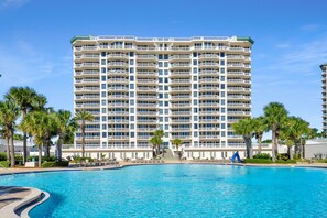 Ein mehrstöckiges Hotel mit einem Schwimmbecken im Vordergrund.