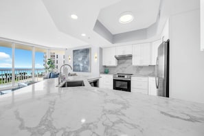 A modern kitchen with white cabinets, a stainless steel refrigerator, and a large island with a sink. - St Croix's Finest ☀️Remodeled 3BR Beachfront⛱️HGTV Worthy🐟Silver Shells😎Amenities🌴 (Destin)