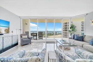 A spacious living room with a large sliding glass door leading to a balcony with a view of the beach and ocean. - St Croix's Finest ☀️Remodeled 3BR Beachfront⛱️HGTV Worthy🐟Silver Shells😎Amenities🌴 (Destin)