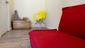 A room with a red sofa, a wooden chest of drawers, a Buddha statue, and a yellow chair. - Adorable 3-bedroom 8 pax cottage in charming Vicuña, Elqui Valley awaits you (Coquimbo)