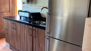 A kitchen with a stainless steel refrigerator, wooden cabinets, and a black countertop. - Adorable 3-bedroom 8 pax cottage in charming Vicuña, Elqui Valley awaits you (Coquimbo)