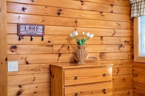 En vägg av trä med en skylt som visar ordet ”SJÖ” och en vas med vita blommor på en byrå av trä.