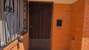 A brick exterior with a metal gate and a doormat.